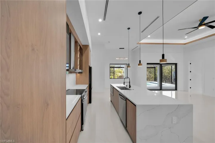 Kitchen featuring modern cabinets, a tray ceiling, a spacious island, range with electric stovetop, and stainless steel dishwasher