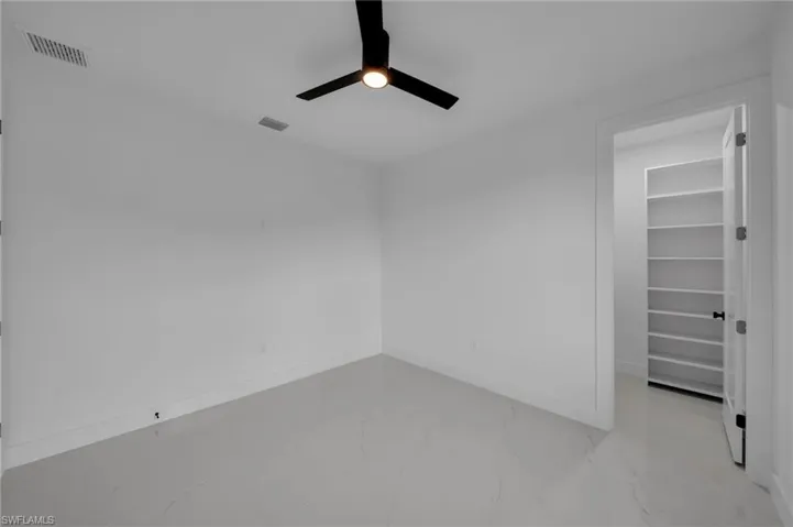Unfurnished room featuring visible vents, baseboards, marble finish floor, and ceiling fan