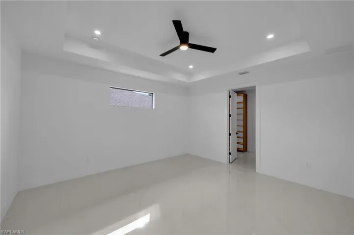 Unfurnished room with recessed lighting, marble finish floor, a raised ceiling, and a ceiling fan