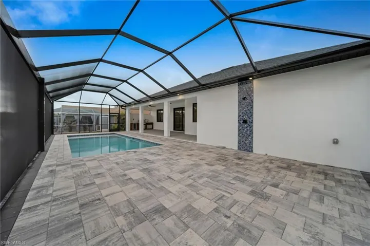 Pool with glass enclosure, a ceiling fan, and a patio