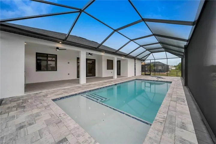 Pool featuring ceiling fan, glass enclosure, and a patio