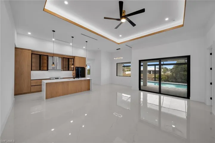 Kitchen featuring brown cabinets, modern cabinets, black refrigerator, a spacious island, and a raised ceiling