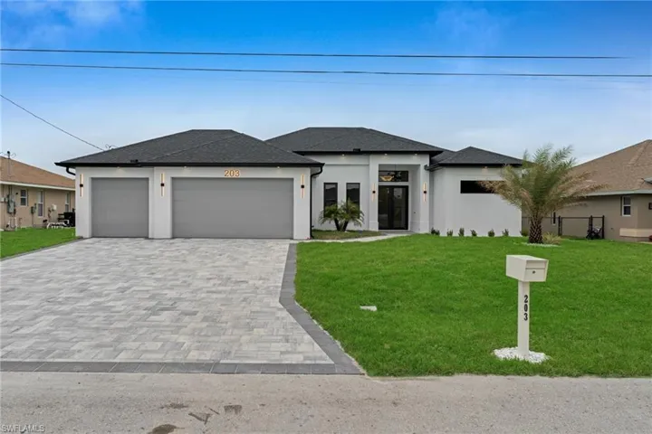 Prairie-style house featuring stucco siding, an attached garage, decorative driveway, and a front lawn