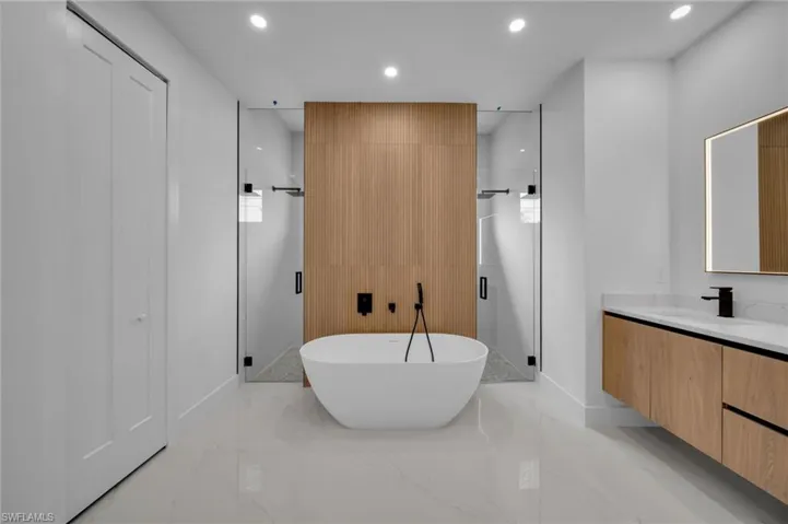 Full bathroom with a freestanding bath, recessed lighting, a stall shower, marble finish floor, and vanity