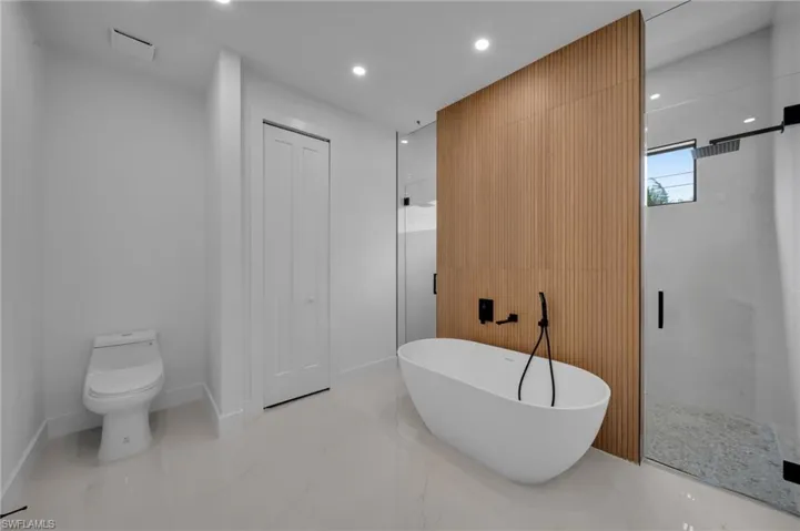 Bathroom featuring a freestanding tub, toilet, marble finish floor, recessed lighting, and a shower stall