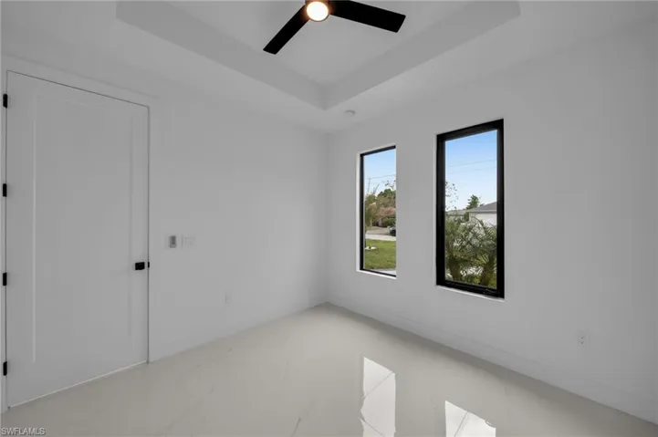Unfurnished room with marble finish floor, baseboards, a tray ceiling, and ceiling fan