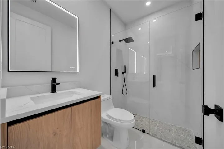 Bathroom with vanity, toilet, and a marble finish shower