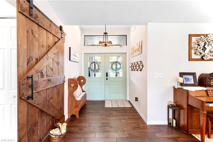 Entryway featuring dark wood-style floors, french doors, baseboards, and a barn door