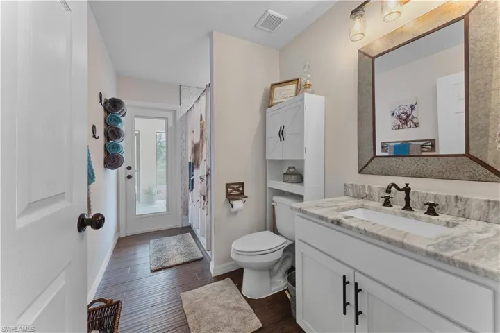 Bathroom with visible vents, toilet, vanity, wood finished floors, and baseboards