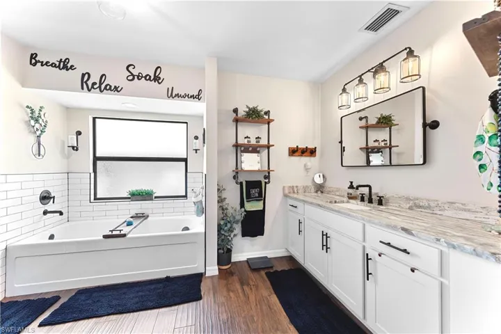 Full bath with a bath, visible vents, wood finished floors, and vanity