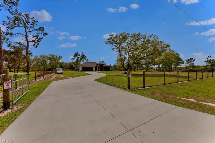 View of front of property with driveway, a garage, a fenced front yard, a gate, and a front lawn