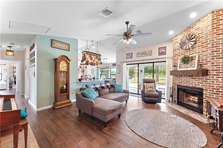 Living room featuring a fireplace, visible vents, a ceiling fan, wood finished floors, and baseboards