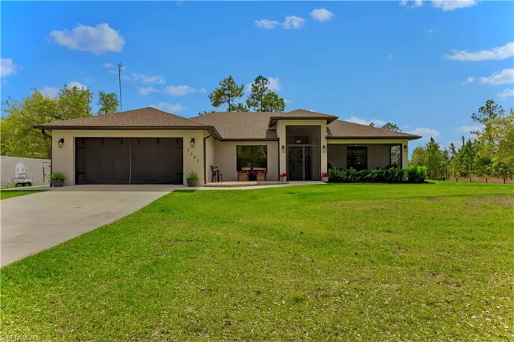 View of front of home featuring a garage, a front yard, concrete driveway, and stucco siding