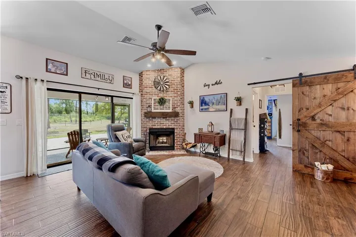 Living area featuring lofted ceiling, wood finished floors, visible vents, and a barn door