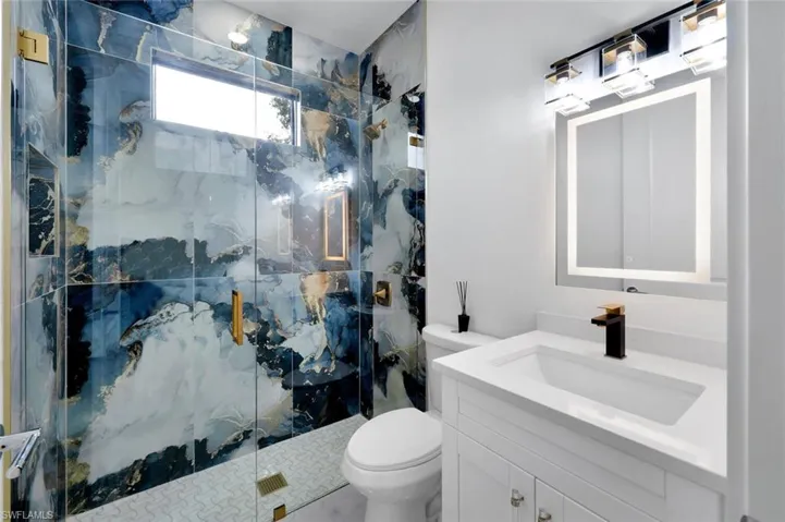 Bathroom with vanity, toilet, and a shower with shower door
