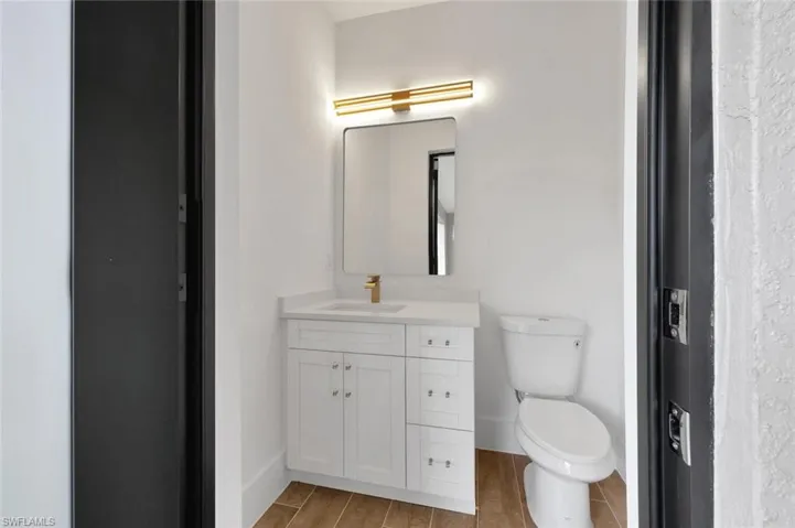 Bathroom with hardwood / wood-style flooring, vanity, and toilet