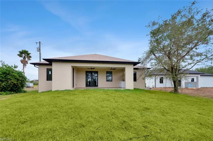 Back of property with ceiling fan and a yard