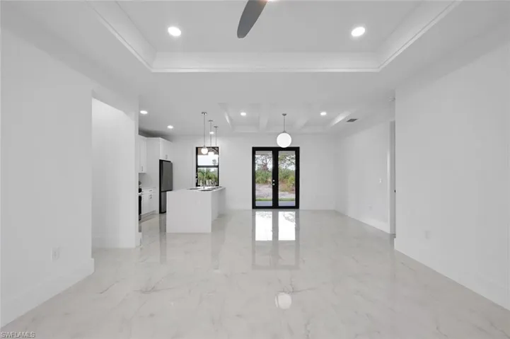Spare room with ceiling fan, a raised ceiling, sink, and french doors