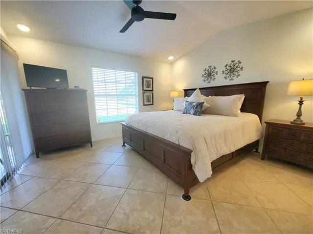 Tiled bedroom featuring ceiling fan and lofted ceiling