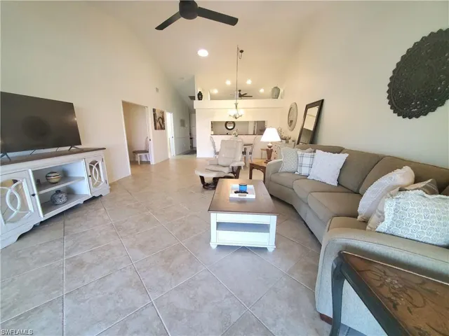 Living room featuring light tile patterned floors, high vaulted ceiling, and ceiling fan