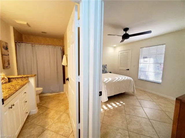 Bathroom featuring tile floors, vanity, ceiling fan, and toilet