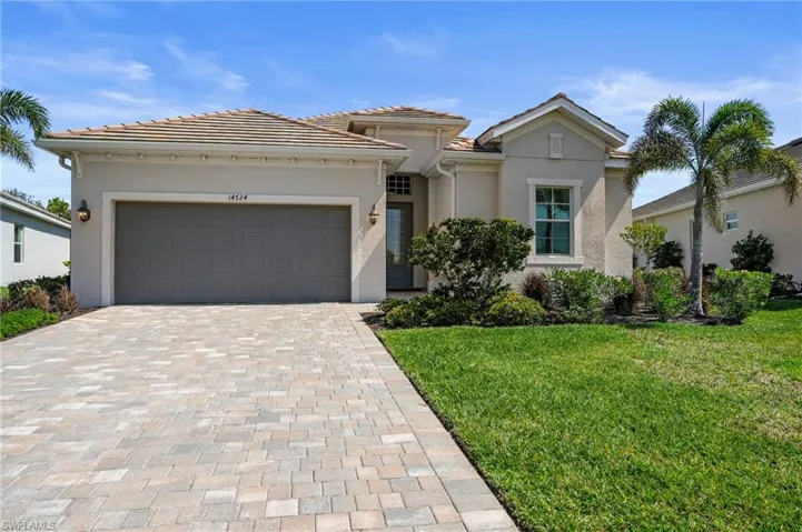 Mediterranean / spanish home with stucco siding, decorative driveway, an attached garage, a front lawn, and a tiled roof