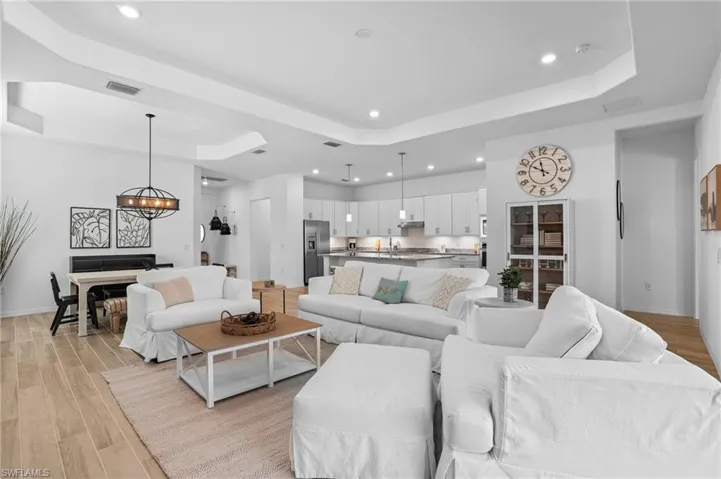 Living area featuring light wood finished floors, a tray ceiling, and recessed lighting