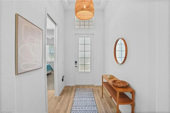 Doorway to outside featuring wood tiled floors and a towering ceiling