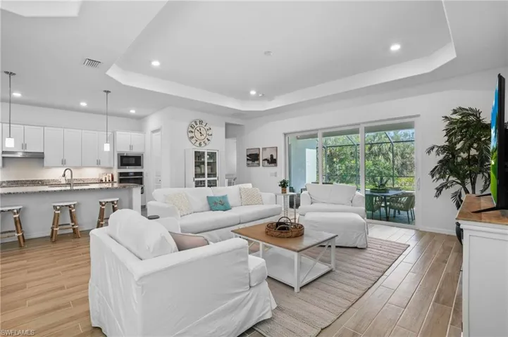 Living room with wood tiled floors, a raised ceiling, and recessed lighting