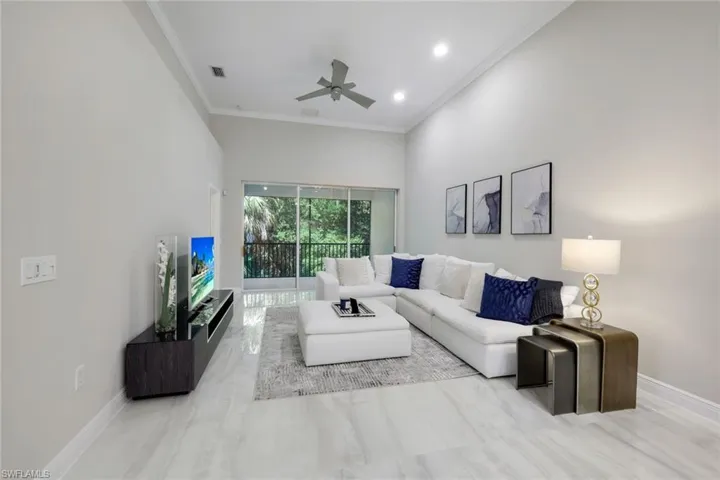 Living room with ceiling fan, ornamental molding, and a high ceiling