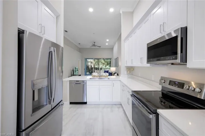 Kitchen featuring kitchen peninsula, white cabinets, ceiling fan, appliances with stainless steel finishes, and sink