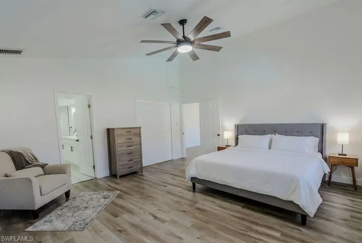 Bedroom featuring light wood-style flooring, ceiling fan, vaulted ceiling, and connected bathroom