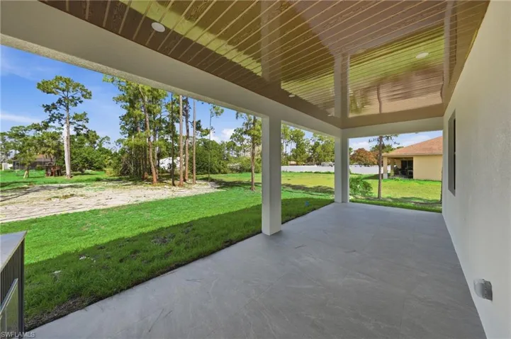 Expansive covered patio featuring a concrete surface, recessed lighting, and built-in outdoor cabinetry with a countertop