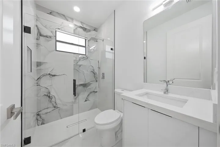 Contemporary bathroom featuring a spacious glass-enclosed shower with marble-style tile surround and a window