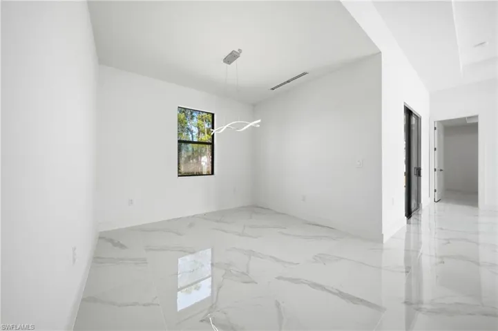 Open interior space featuring large format marble-look tile flooring, white walls, and a modern linear pendant light fixture