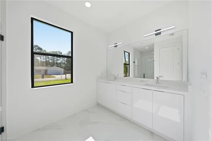 Dual vanity featuring white cabinetry, integrated sinks, and polished chrome fixtures