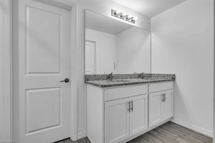 Bathroom featuring light wood finished floors, vanity,  shower combination, and recessed lighting