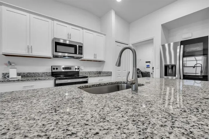 Kitchen featuring dark stone countertops, an island with sink, stainless steel appliances, open floor plan, and recessed lighting
