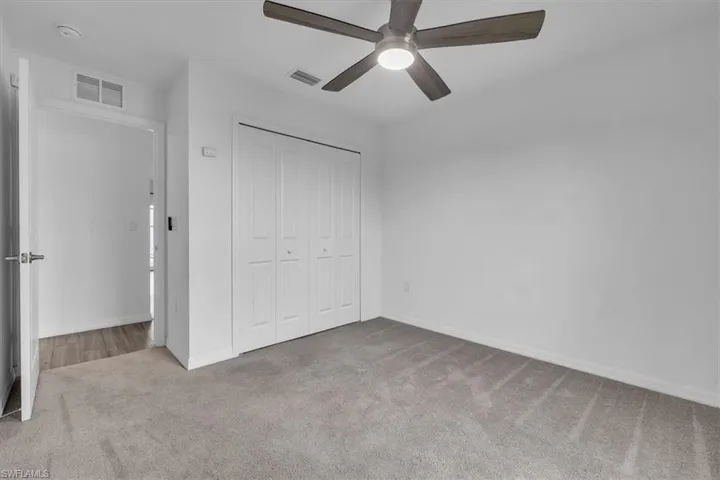Unfurnished bedroom with light carpet, a closet, and ceiling fan
