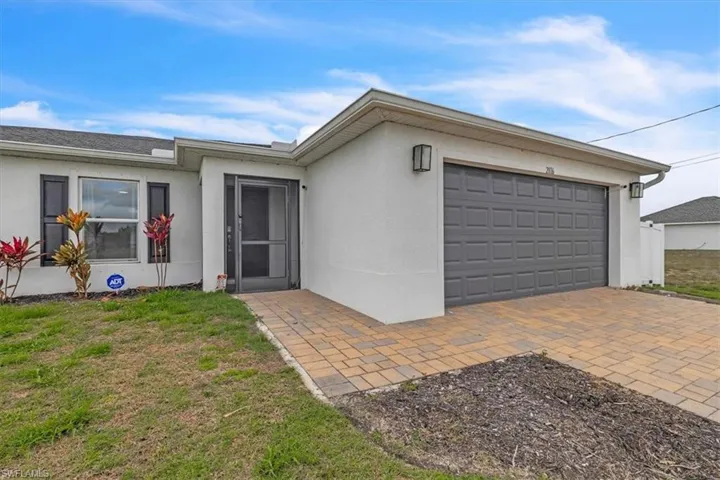 View of front of property with stucco siding, a front lawn, and an attached garage