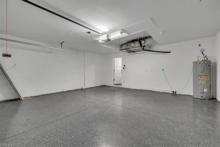 Garage featuring electric water heater and a garage door opener