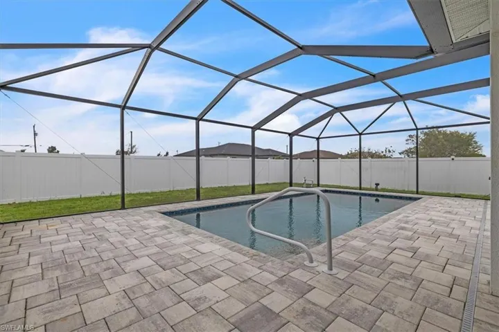 View of swimming pool with a sunroom, glass enclosure, a fenced backyard, and patio surround