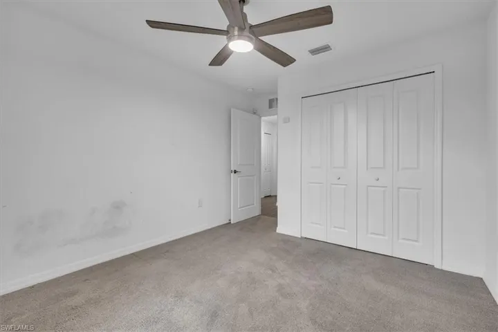 Unfurnished bedroom with light carpet, a closet, and a ceiling fan