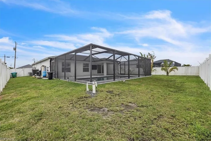 Rear view of property with a sunroom, a fenced backyard, glass enclosure, and a swimming pool