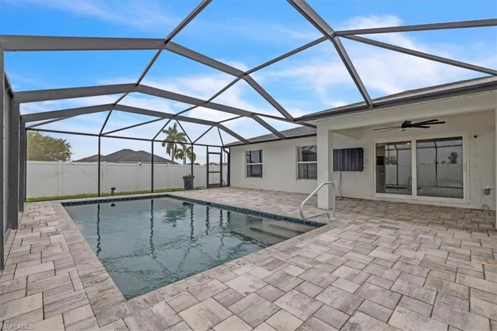 View of pool featuring a sunroom, glass enclosure, and patio surround