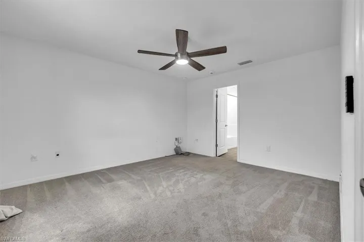 Unfurnished room with ceiling fan and light colored carpet