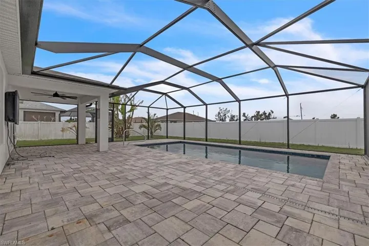 View of pool featuring a fenced backyard, glass enclosure, a sunroom, and patio surround