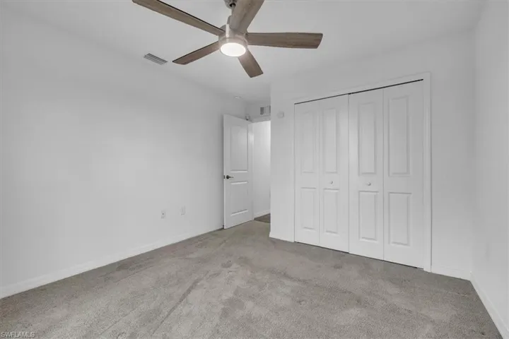 Unfurnished bedroom featuring light colored carpet, a closet, and ceiling fan