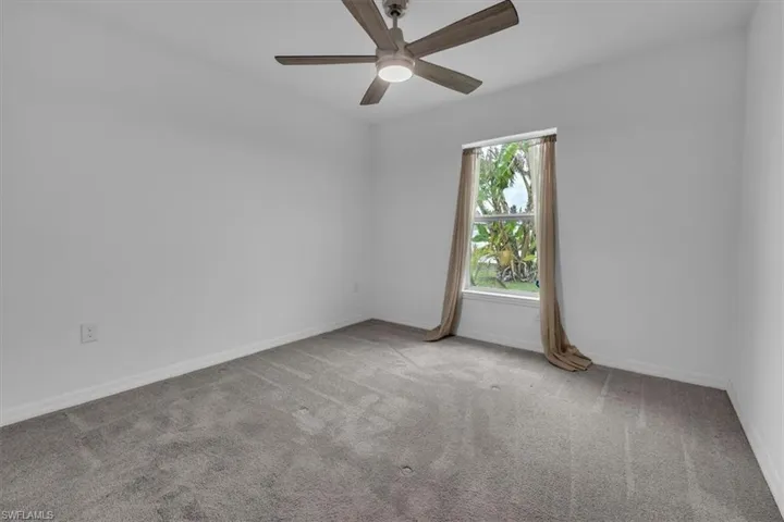 Empty room featuring light colored carpet and a ceiling fan
