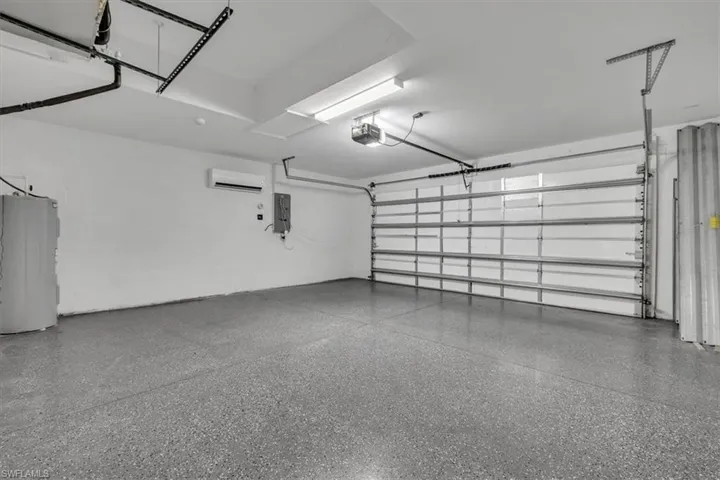 Garage featuring water heater, electric panel, and a garage door opener